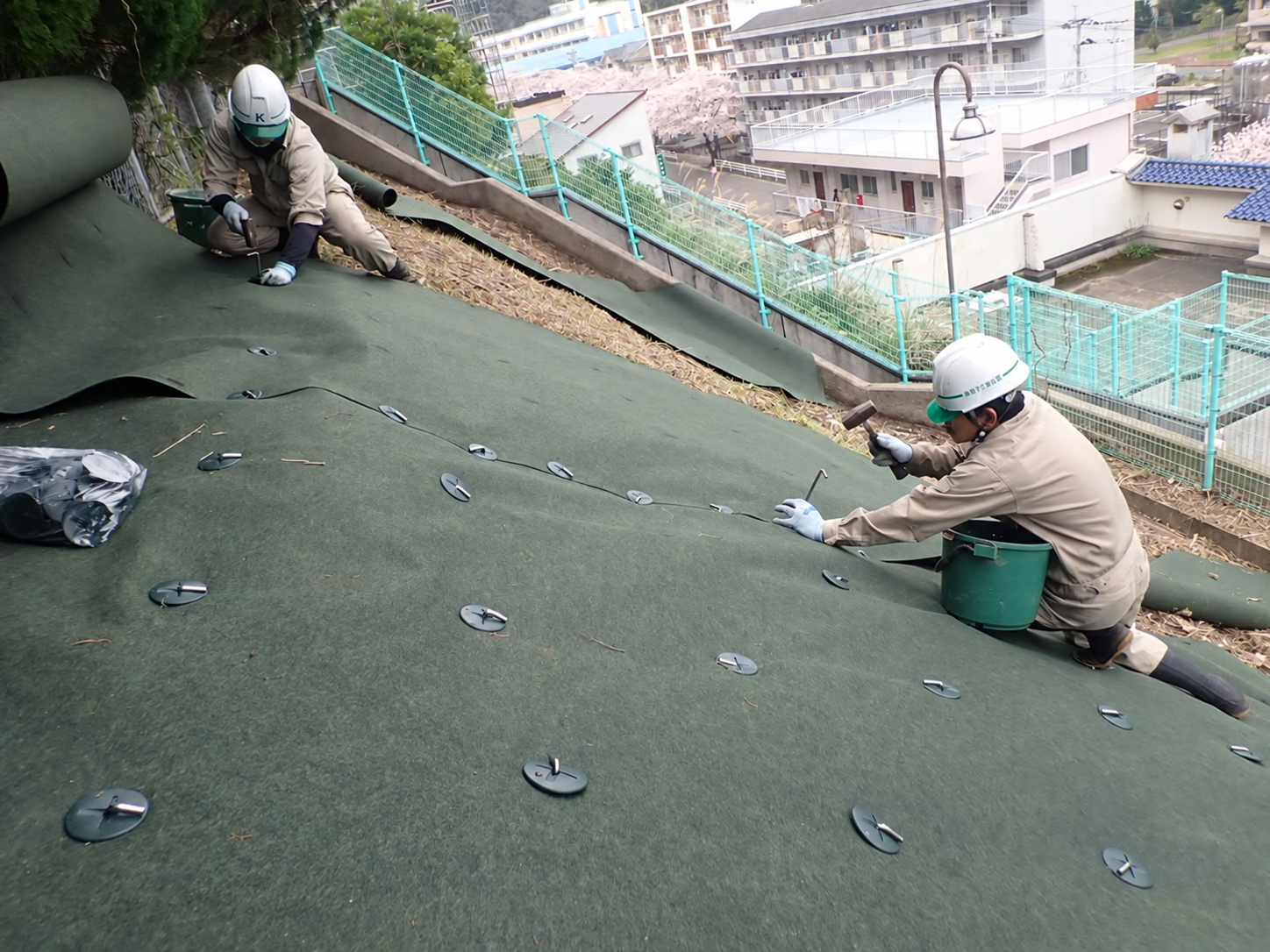 斜面に防草シートを固定する作業|金子兄弟造園